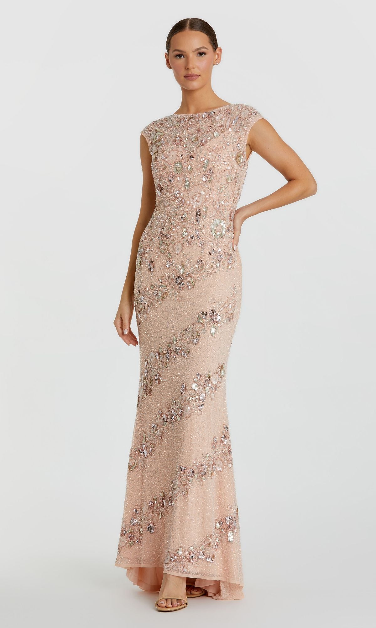 A woman poses against a plain white background wearing the Mac Duggal 5500 Beaded Long Formal Dress—a sleeveless, floor-length blush pink gown adorned with sequins and floral patterns.